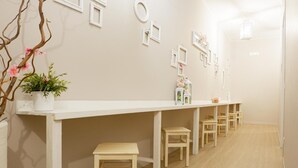 Un long comptoir d’accueil blanc, agrémenté de plusieurs chaises et d’une plante en pot.