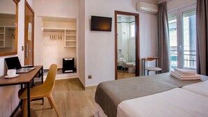 A hotel room with a bed, a desk with a laptop and a cup, a chair, a wardrobe, a television, and a window with curtains. - Hotel Ramis (Ondara)