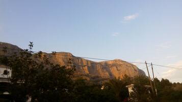 A mountain with a clear sky. There are power lines and some vegetation in the foreground.