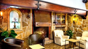 A cozy interior with stone walls, a fireplace, leather chairs, and a wooden coffee table. - Hotel Ramis (Ondara)