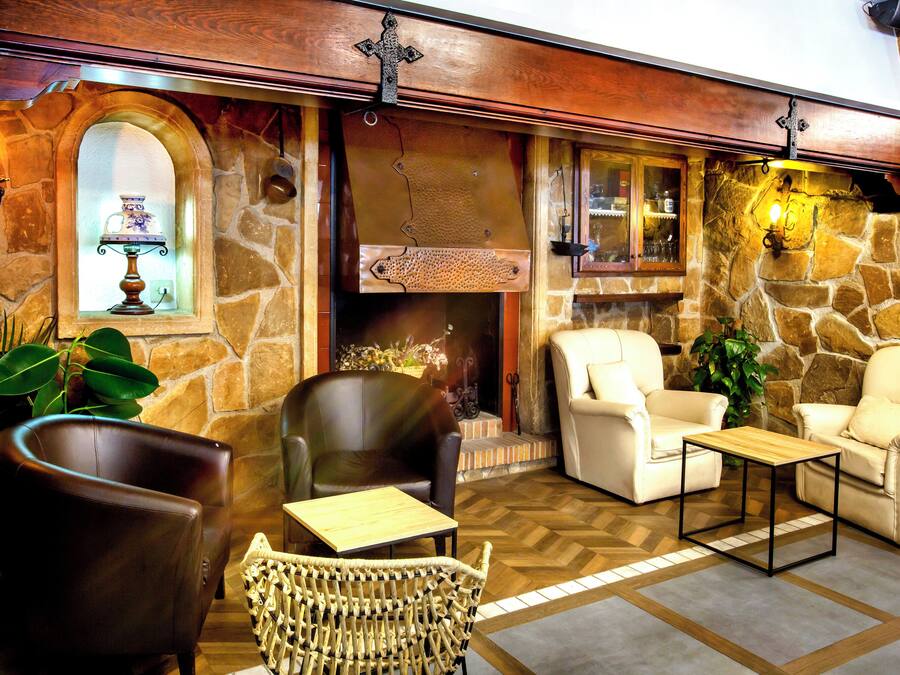 A cozy interior with stone walls, a fireplace, leather chairs, and a wooden coffee table.