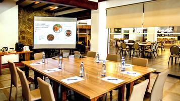 Una sala de conferencias con una mesa grande, sillas, una pantalla de proyector y una estación de café.