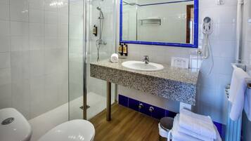 Un baño moderno con cabina de ducha de vidrio, lavabo con encimera de granito y espejo con marco azul.