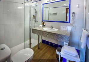 Un baño moderno con cabina de ducha de vidrio, lavabo con encimera de granito y espejo con marco azul.