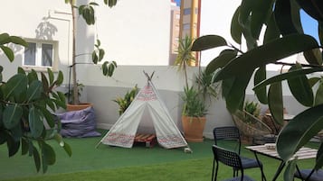Een binnenplaats met kunstgras, een tipi, potplanten en tuinmeubilair.