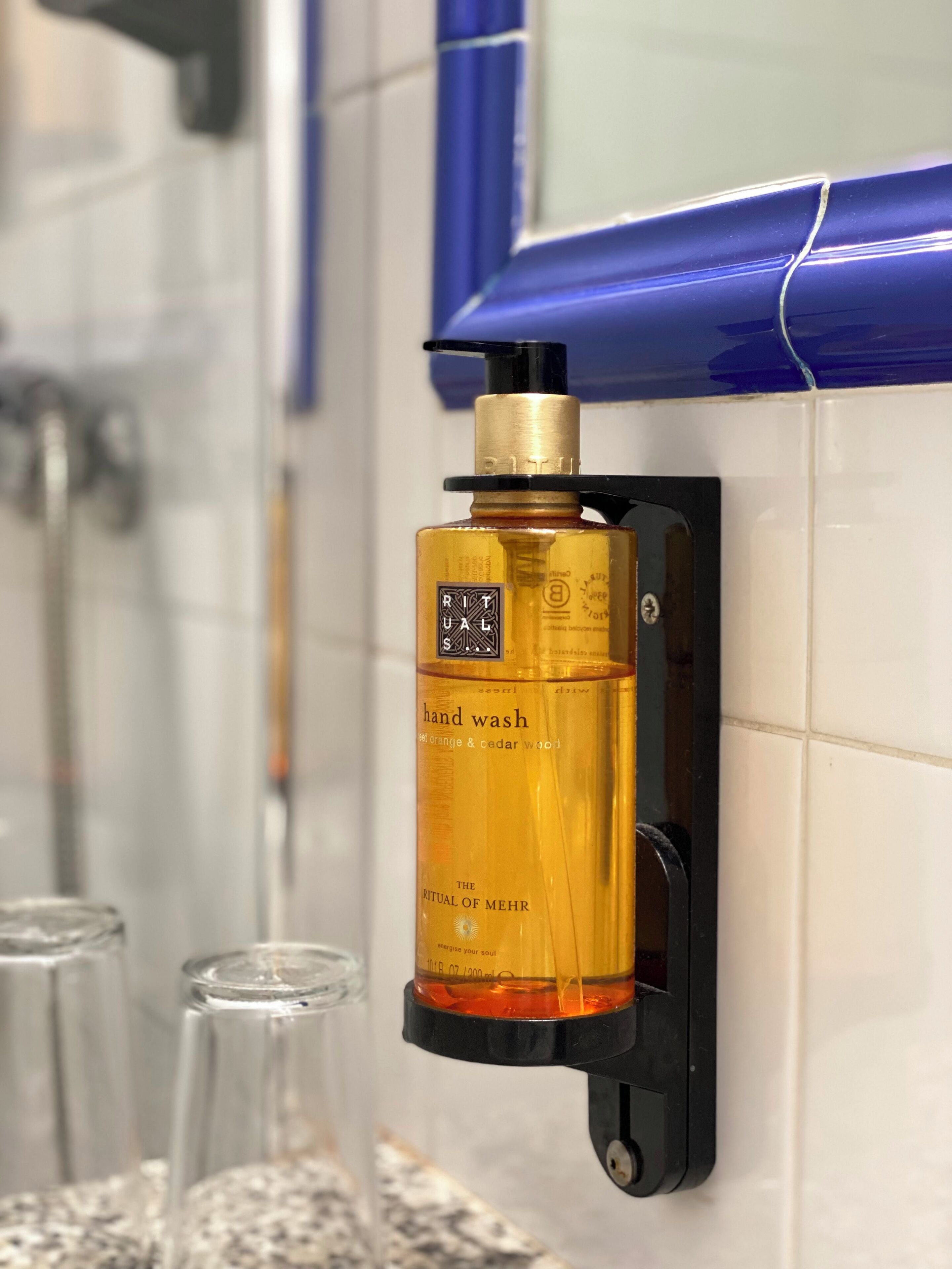 A hand wash dispenser mounted on a bathroom wall.