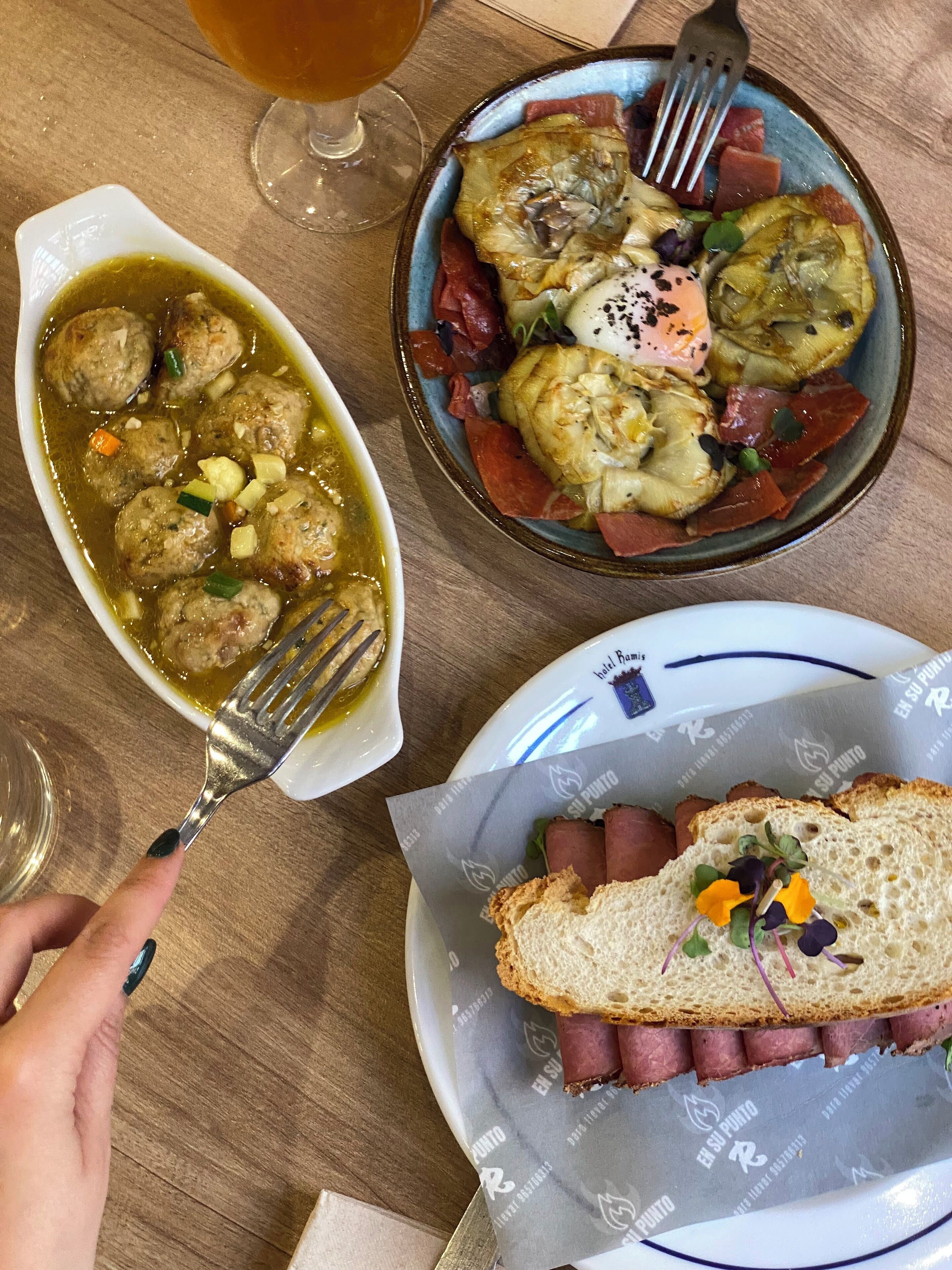 A meal with meatballs in a sauce, a plate with vegetables and meat, and a sandwich with meat and greens.