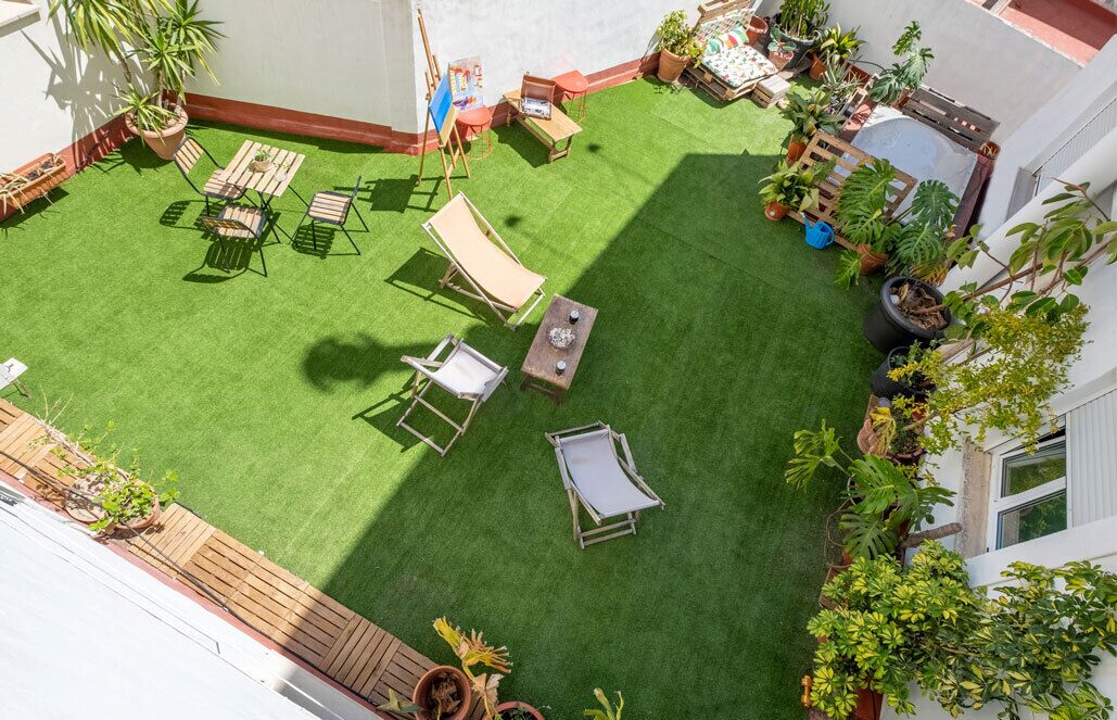 A rooftop garden with artificial grass, outdoor furniture, and potted plants.