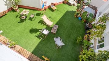 A rooftop garden with artificial grass, outdoor furniture, and potted plants.