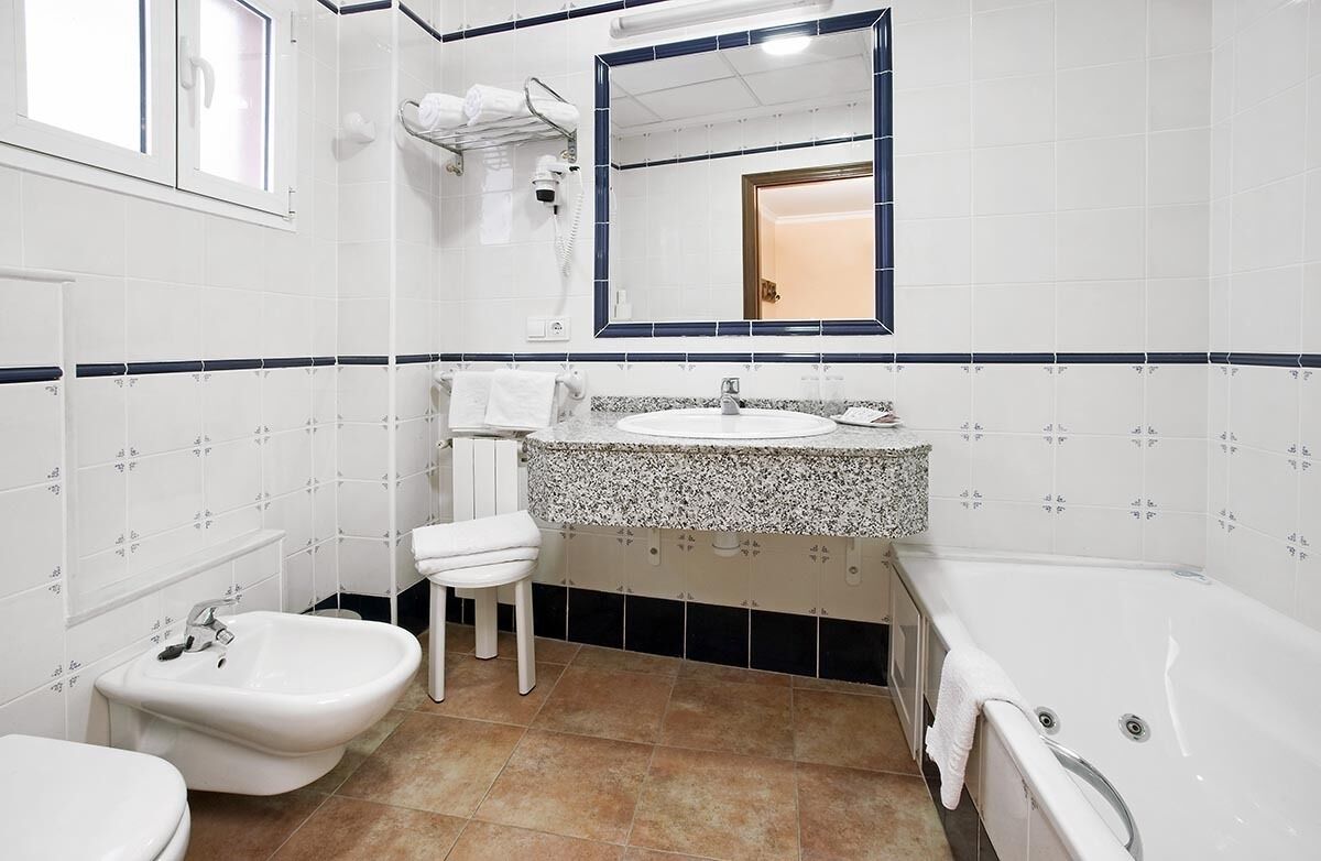 Un baño con bidé, lavamanos, espejo y bañera.