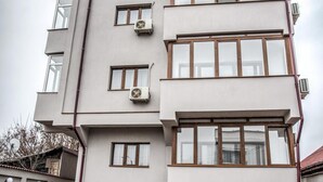 Un edificio de varios pisos con un patio de ladrillo, unidades de aire acondicionado y un techo plano.