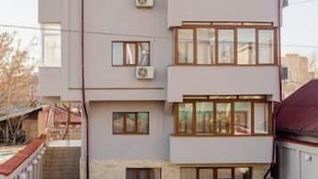 A multi-story residential building with a flat facade, multiple windows, and a gated entrance.