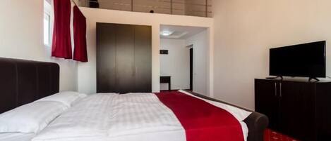 A hotel room with a bed, a TV, a wardrobe, and a balcony.