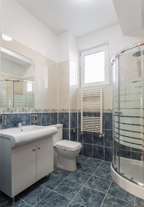 A modern bathroom with a glass shower enclosure, a white sink, and a toilet. - Hotel Elisabeta (Bucharest)