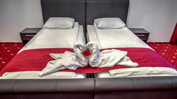 Una cama doble con una colcha roja y dos almohadas blancas.