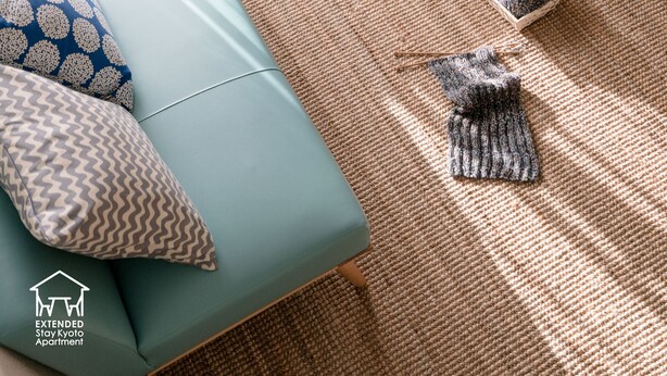 A living room with a sofa, a woven rug, and a basket of yarn. - EXTENDED Stay Kyoto Apartment (Kyoto)