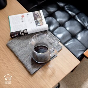 A table with a glass of coffee, a magazine, and a herringbone-patterned placemat. - EXTENDED Stay Kyoto Apartment (Kyoto)