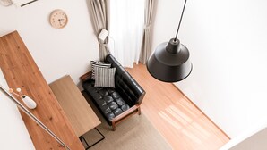 A modern living room with a black leather sofa, wooden side table, and a black floor lamp. - EXTENDED Stay Kyoto Apartment (Kyoto)
