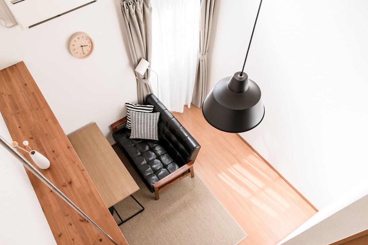Un salon moderne avec un canapé en cuir noir, une table d’appoint en bois et un lampadaire noir.