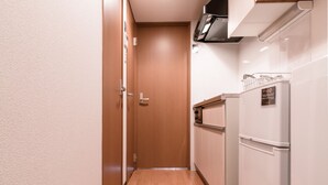 A narrow hallway with wooden flooring, a white refrigerator, and a microwave on the right. - EXTENDED Stay Kyoto Apartment (Kyoto)