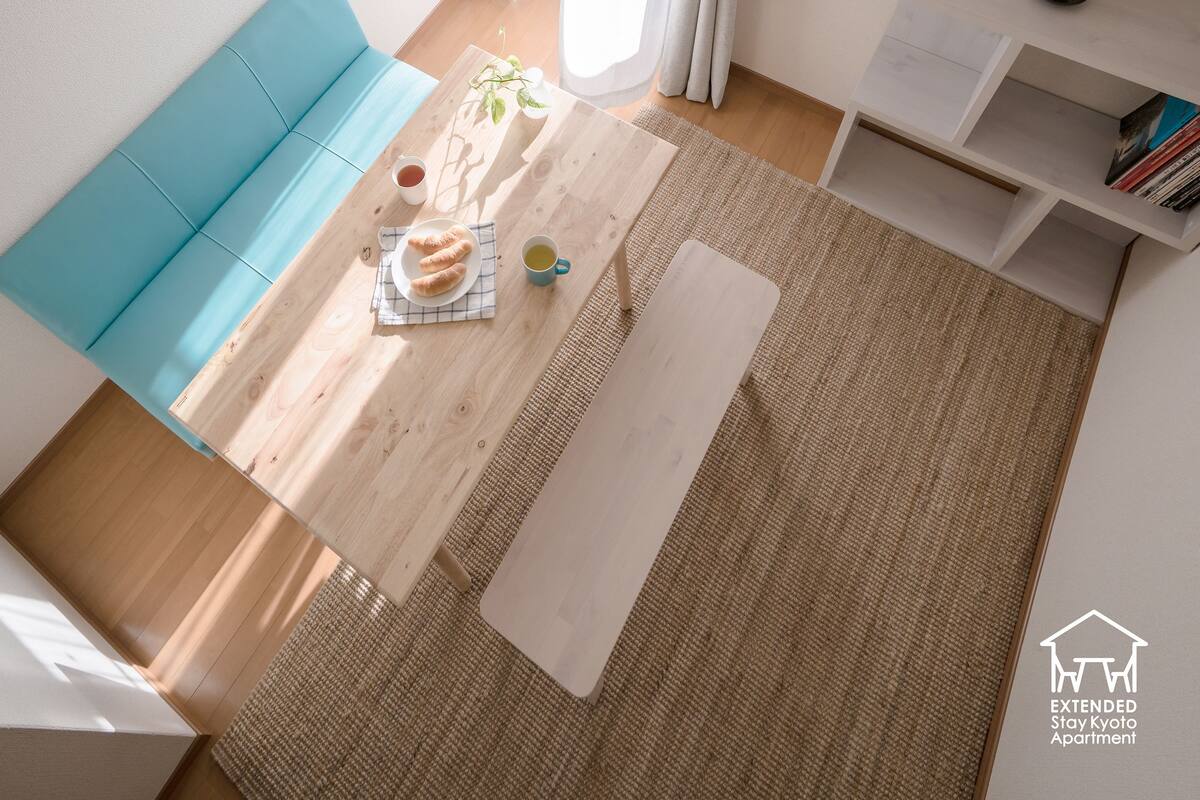 Un salon moderne avec un canapé bleu, une table basse en bois et une petite bibliothèque.