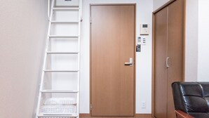 A staircase with a handrail, a wooden door with a keypad lock, and a black leather chair. - EXTENDED Stay Kyoto Apartment (Kyoto)