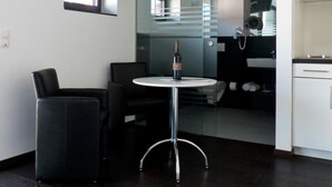A modern kitchen with a glass partition, a dining area with a round table, and a flat-screen TV mounted on the wall. - Porta Vinea (Ruppertsberg)