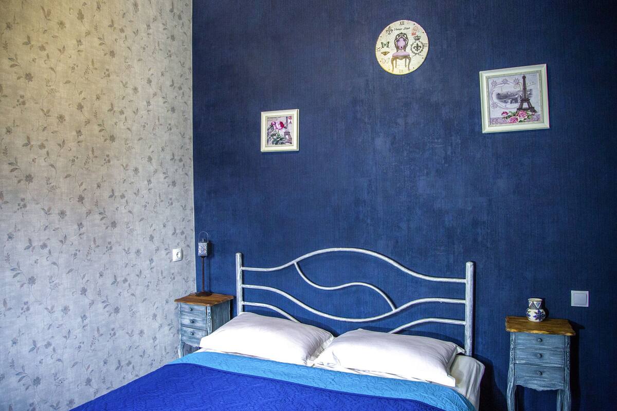 A bedroom with a bed, two nightstands, and floral wallpaper.