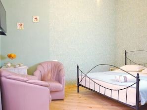 A bedroom with a bed, a chair, a small table with a vase of flowers, and a wall with a floral pattern. - Terrace Garden (Tbilisi)