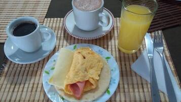 A breakfast setting with a plate of food, a cup of coffee, and a glass of orange juice on a table.