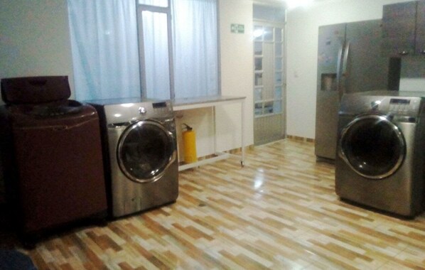 Une buanderie équipée de deux machines à laver, d’un sèche-linge et d’un petit meuble de rangement.