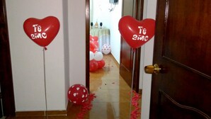 Un umbral decorado con globos rojos con forma de corazón y una alfombra roja que conduce a una habitación.