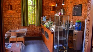 A cozy kitchen with a brick wall, wooden counter, and a window with green curtains. - Raj Mahal Inn (Wadduwa)