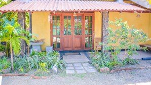 A house with a tiled roof, a wooden door, and a small garden with plants and a stone pathway. - Raj Mahal Inn (Wadduwa)