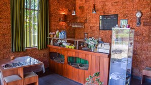 A rustic kitchen with wooden walls, a bar area, and a refrigerator. - Raj Mahal Inn (Wadduwa)
