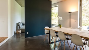 A modern dining area with a long wooden table, white chairs, and a dark accent wall. - Dimensions M (Mont-Saint-Guibert)