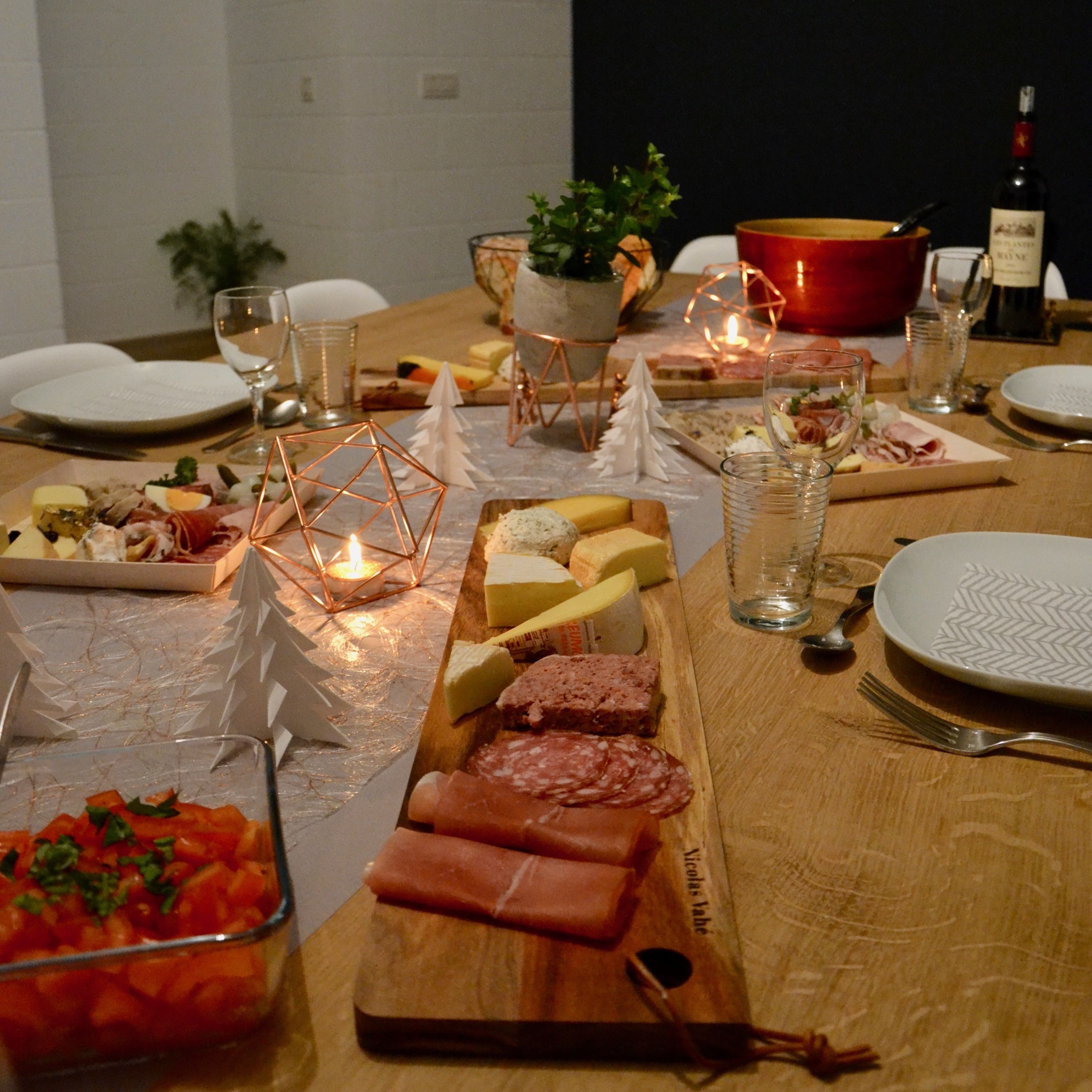 Een eettafel gedekt voor een maaltijd, met verschillende kazen, vleessoorten en een glas wijn.
