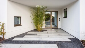 A modern building entrance with a glass door, a small potted plant, and a pathway leading to the door. - Dimensions M (Mont-Saint-Guibert)