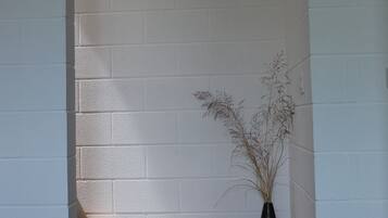 A corner with white brick walls, a wooden bench, and a black vase with dried plants.