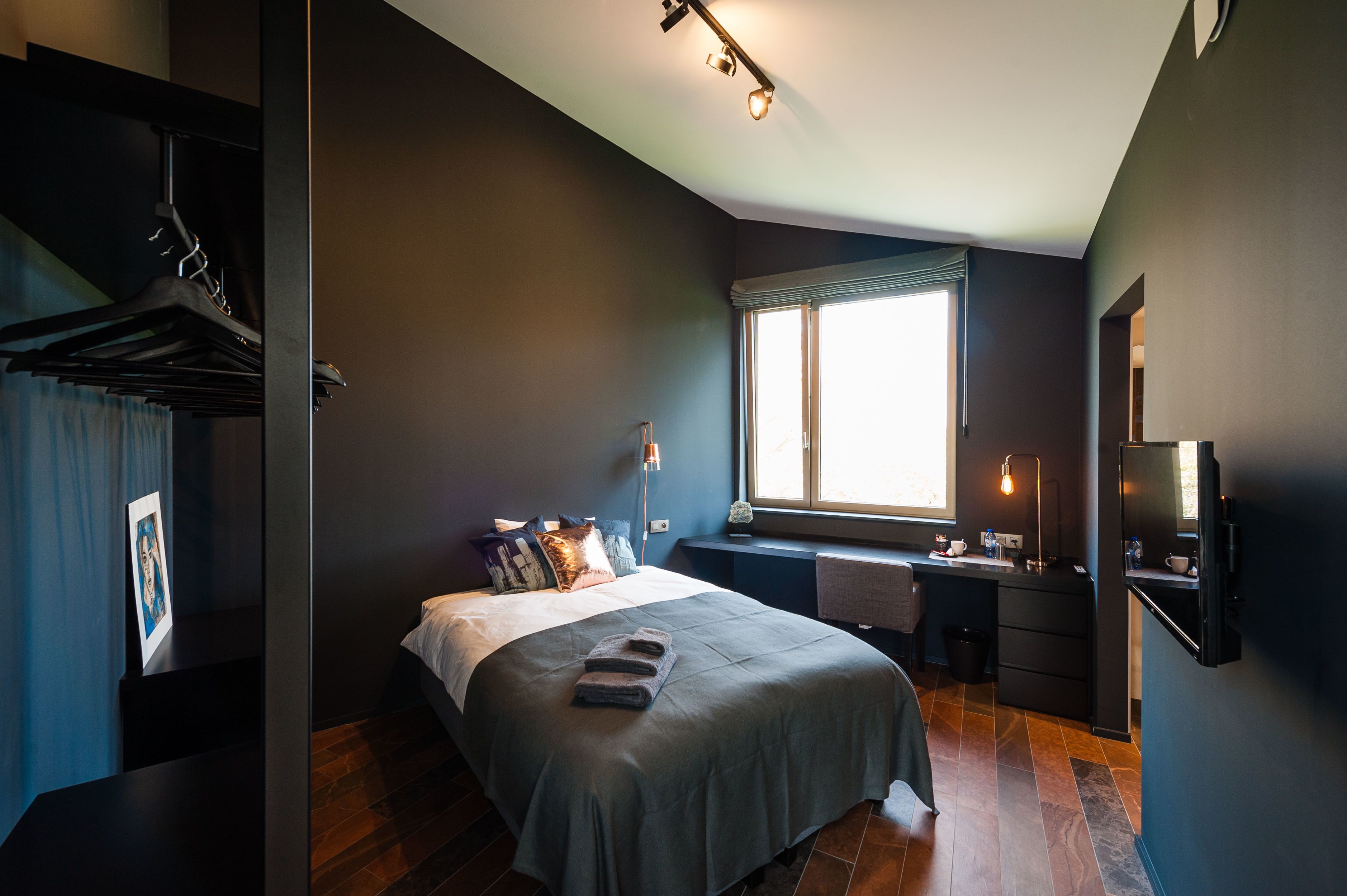 A modern bedroom with a bed, bedside table, and a window.