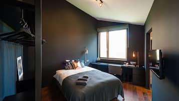 A modern bedroom with a bed, bedside table, and a window.