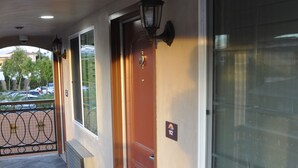 A hotel corridor with a wooden door, a large window, and a metal railing. - Sun Light Motel (Downey)