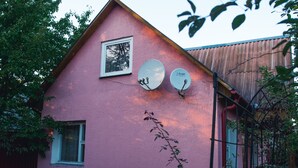 Une maison rose avec deux antennes paraboliques et une fenêtre.