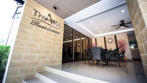 A restaurant entrance with a stone facade, a glass door, and a seating area with wicker chairs and a table. - Thana Residence Lam Luk Ka (Lam Luk Ka)