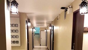 A hotel hallway with a shiny tiled floor, wall-mounted light fixtures, and a staircase at the end. - Thana Residence Lam Luk Ka (Lam Luk Ka)