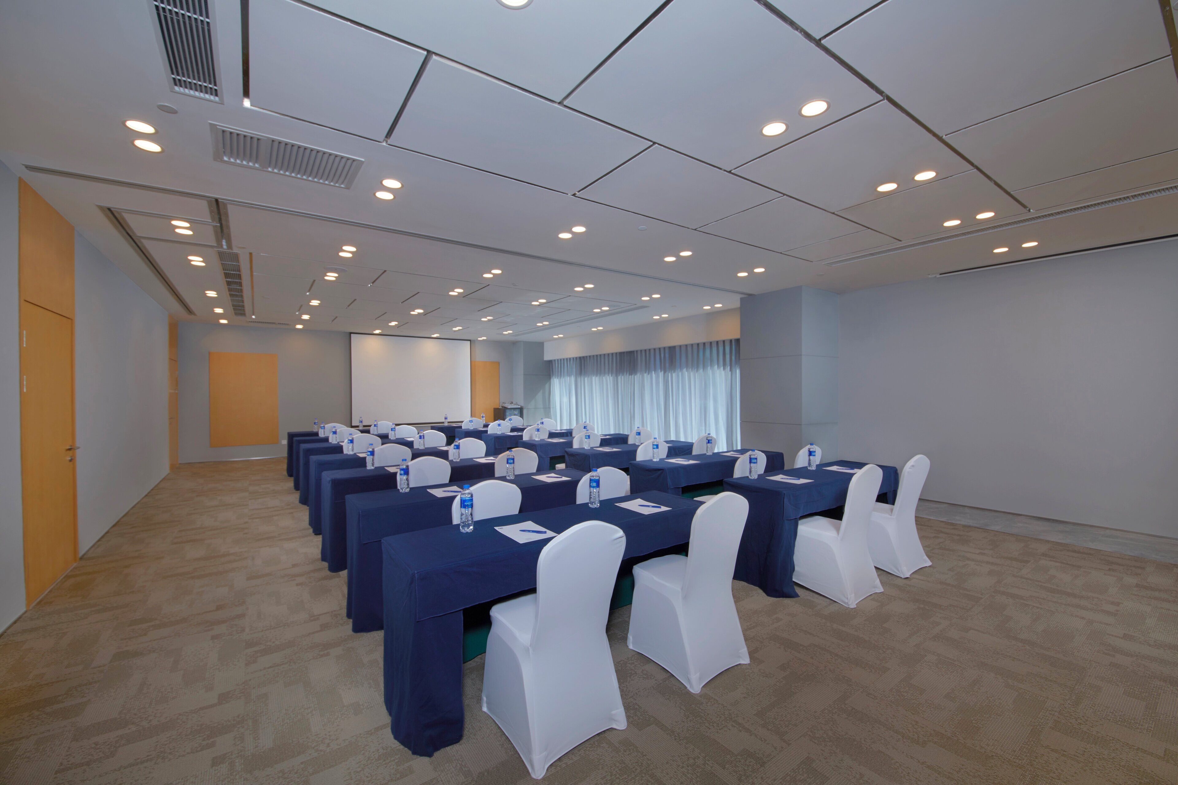 A conference room with multiple tables and chairs, equipped with water bottles and nameplates.