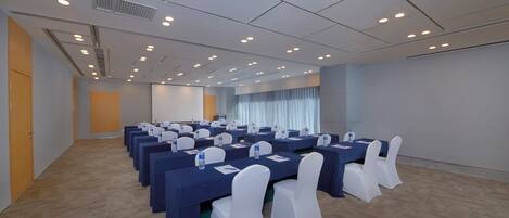 A conference room with multiple tables and chairs, equipped with water bottles and nameplates.