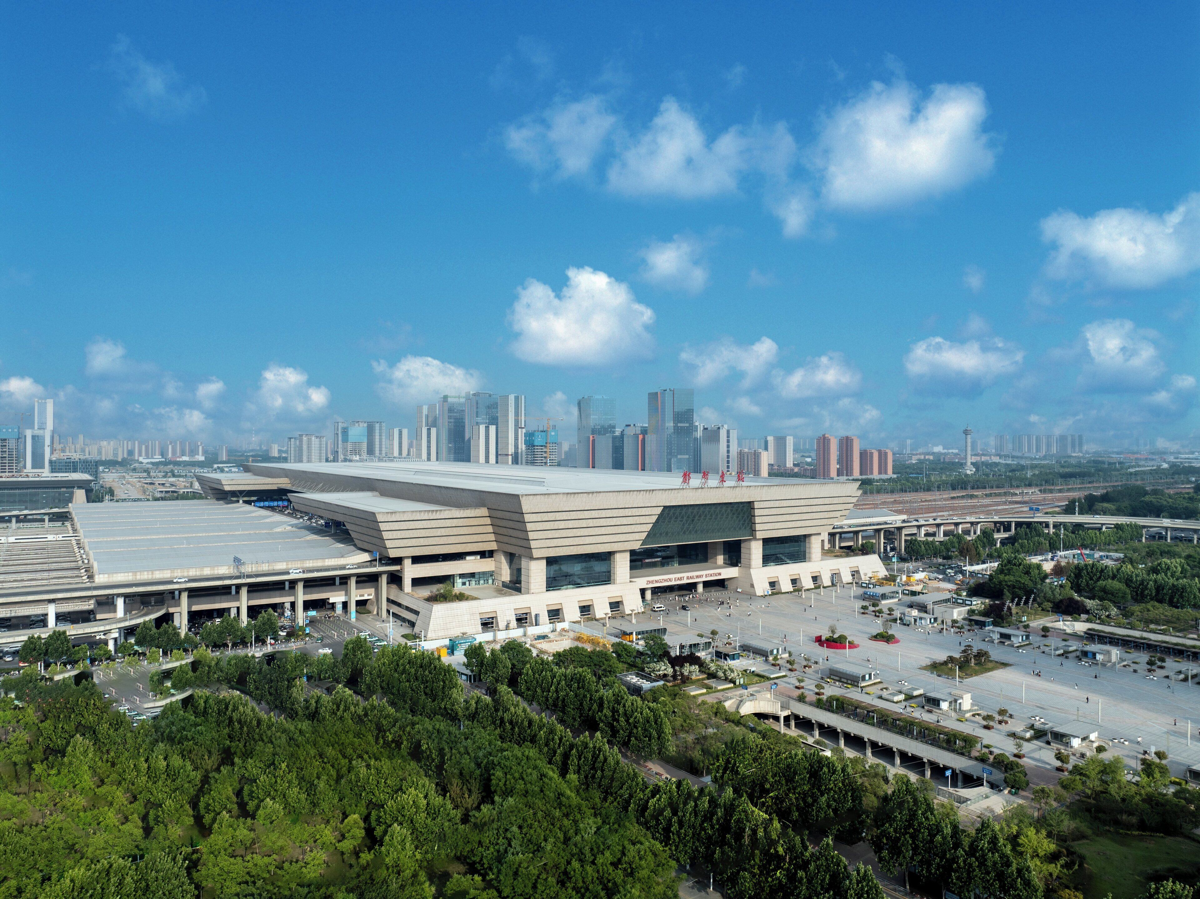 A modern train station with multiple platforms and a large building in the foreground.