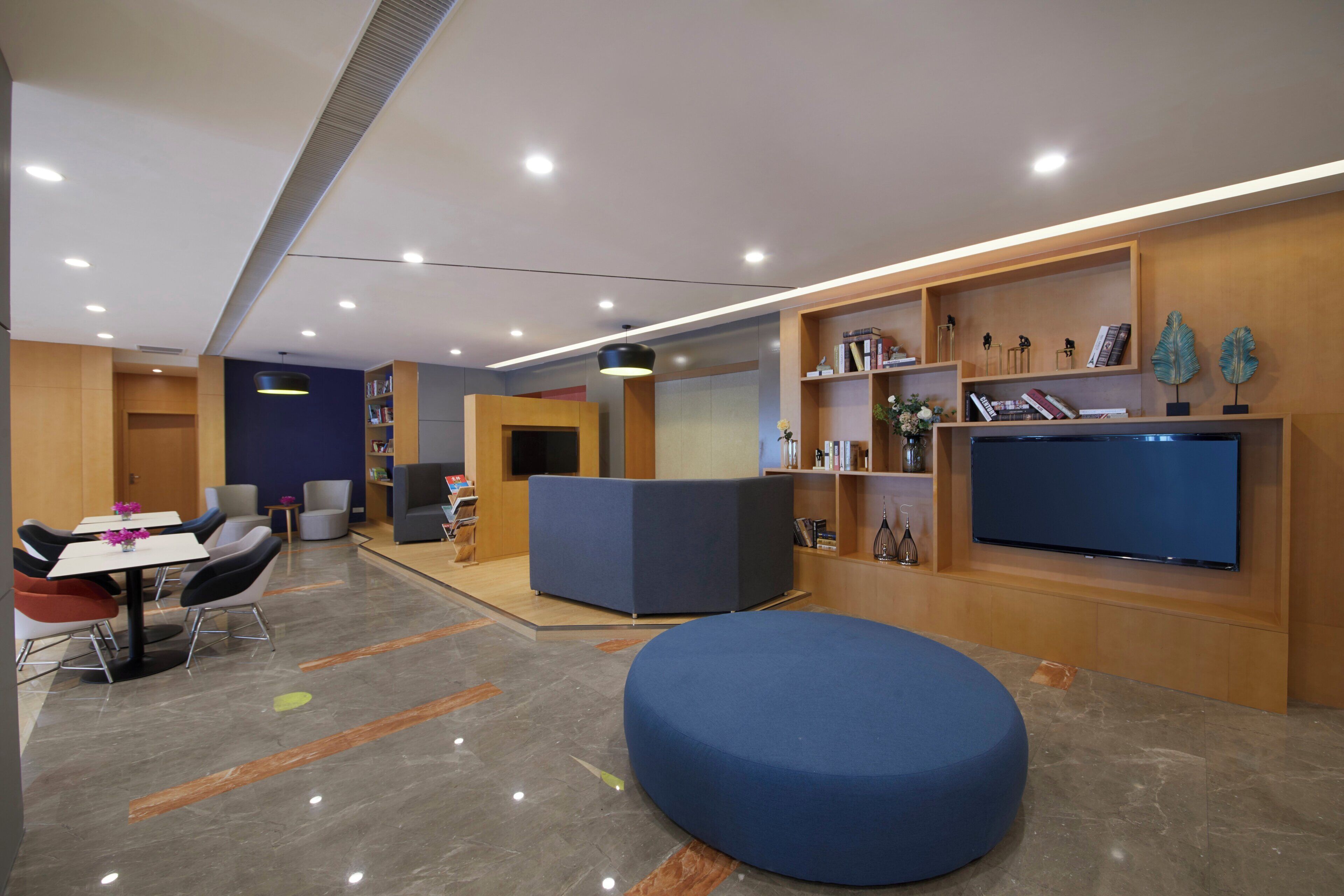 A modern lobby with a reception desk, seating area, and a television.