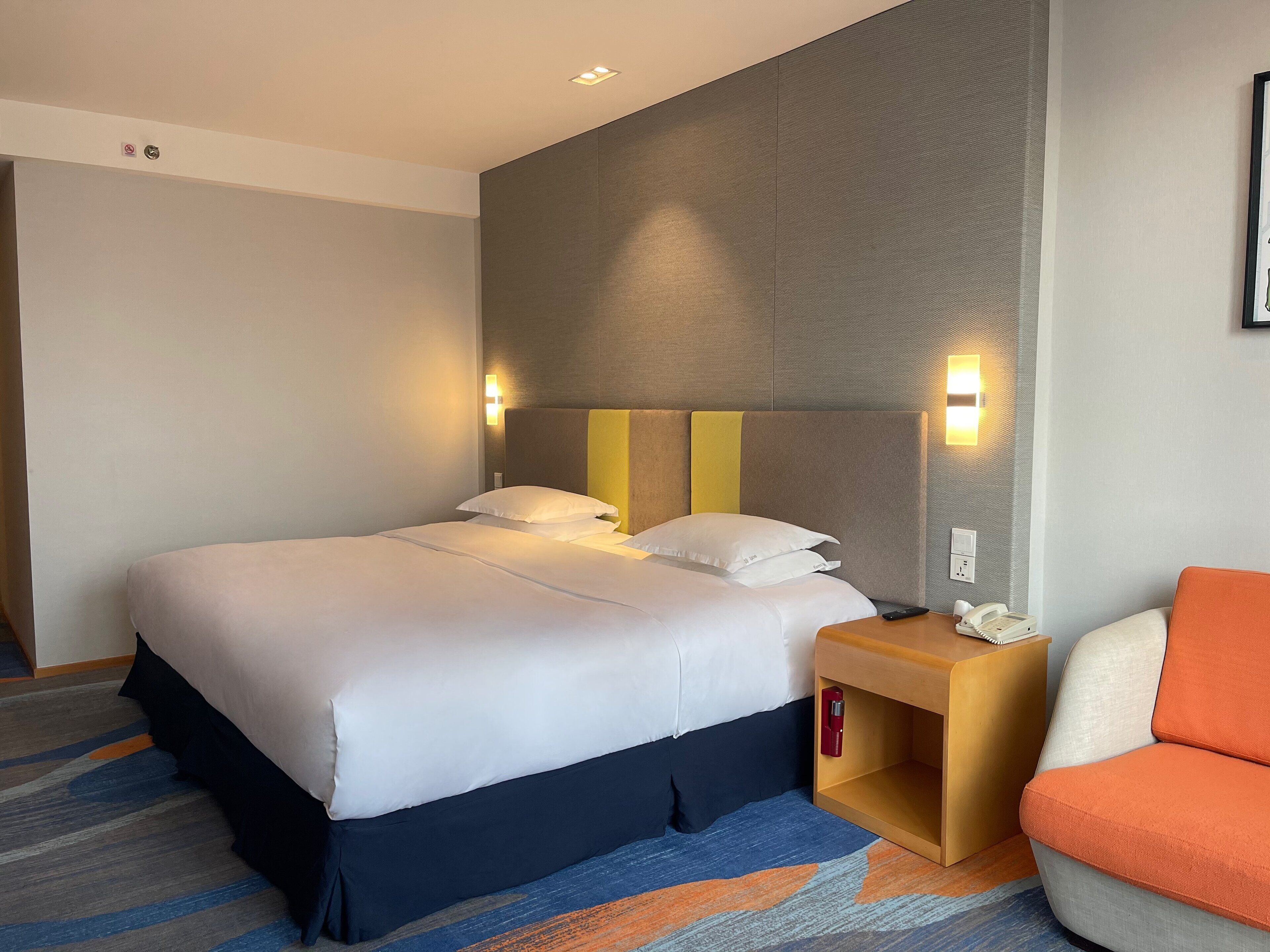 Ein Hotelzimmer mit einem Bett, einem Nachttisch und einem orangefarbenen Sessel.